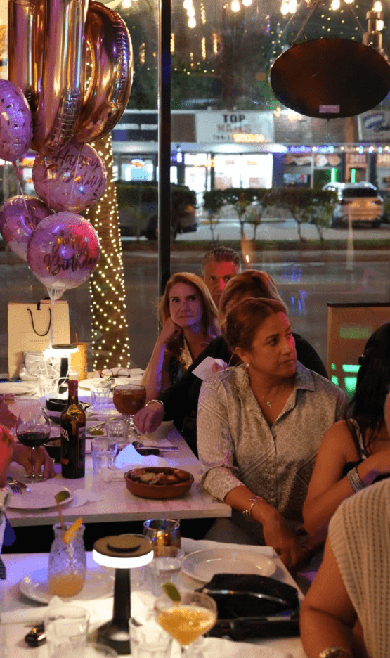 Birthday celebration table with balloons, sangria, and shared plates by the window at Tiempo D' Tacos on Calle Ocho