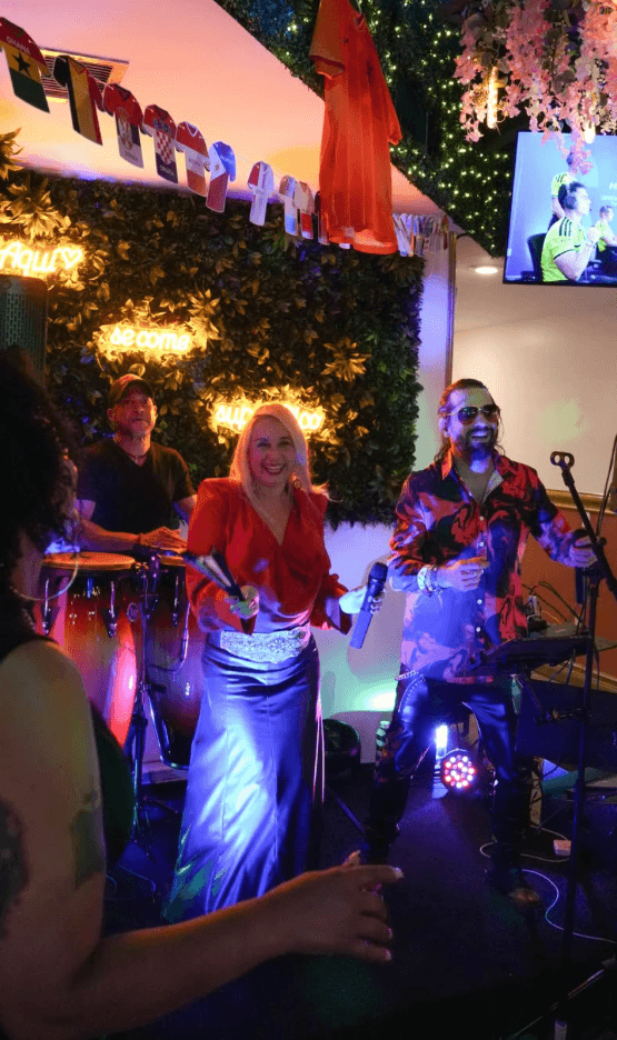 Monteros performing live with congas and maracas in front of the neon wall at Tiempo D' Tacos, Little Havana